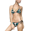 Woman wearing a black and white patterned bikini with turquoise accents on a white background